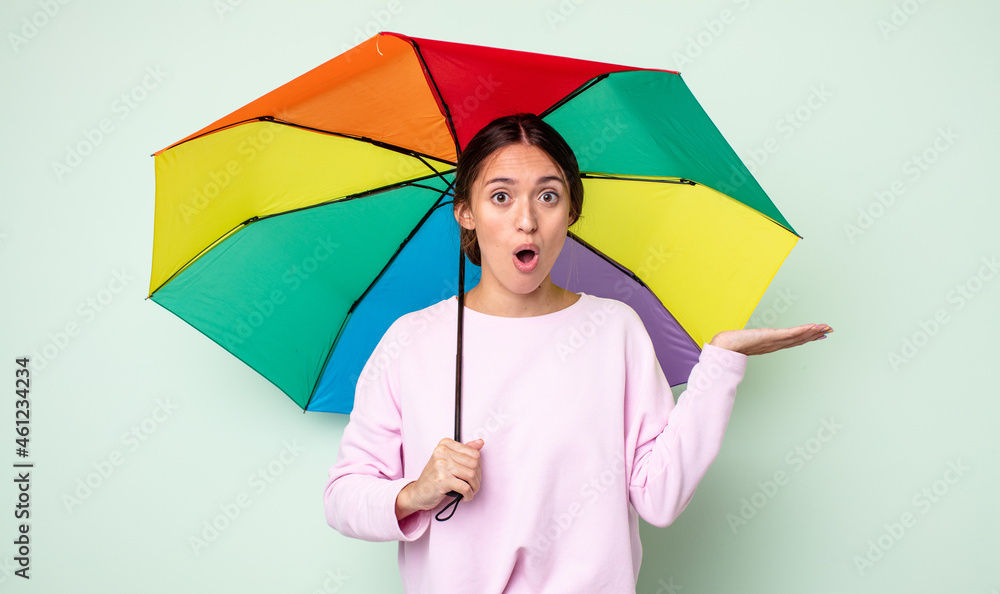 Sticker young pretty woman looking surprised and shocked, with jaw dropped holding an object. umbrella concept