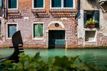 Traditional gondola on the narrow canal in Venice, Italy. Exploring beautiful Venice on water on a sunny day.