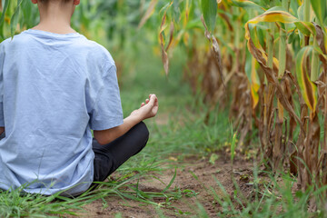 Closeup of kid hand meditating on nature. Kid boy Half Lotus pose yoga meditating on grass in summer day. Health, meditation and relaxation concept.