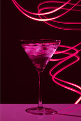 Martini glass with drink and ice against creative lighting