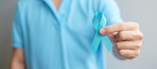 November Prostate Cancer Awareness month, Man in blue shirt with hand holding Blue Ribbon for...