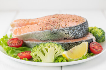 Raw uncooked salmon steak with fresh vegetables.