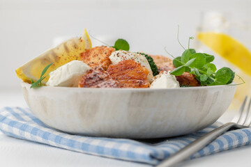 Baked salmon fillet salad with fresh vegetables, cream cheese, lemon, and microgreens.