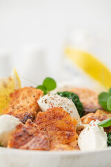 Baked salmon fillet salad with fresh vegetables, cream cheese, lemon, and microgreens.