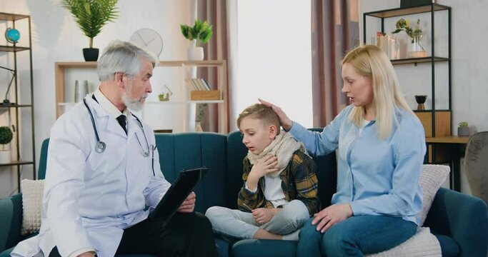 Medicine and healthcare concept where respected skilled bearded doctor visiting his child patient at home and listening about desease symptoms from caring mother