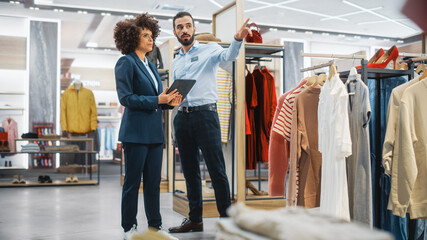 Clothing Store: Businesswoman Uses Tablet Computer, Talks to Visual Merchandising Specialist, Collaborate To Create Stylish Collection. Small Business Fashion Shop Sales Manager Talks to Designer.