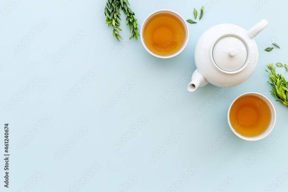 Wall mural Tea drinking with white teapot and two cups with green leaves, top view