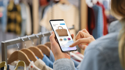 Clothing Store: Female Using Smartphone with Online Fashion Store User Interface to Chek Prices on...
