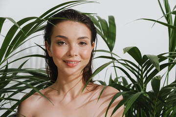 Young half-naked woman posing with plants on camera
