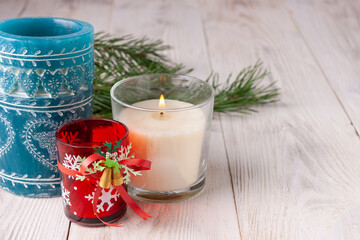 candles in glass jars stand on a light wooden background