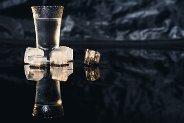 Vodka shot with ice on black table, copy space