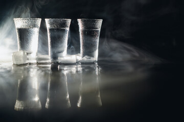 three Vodka shots with ice on black table, copy space
