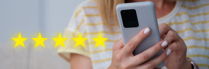 Woman holding mobile phone in her hands and giving five star rating for quality of services closeup