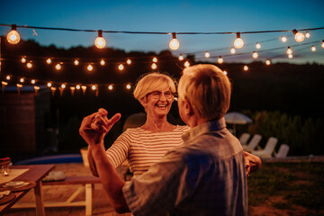 Senior couple dancing outdoors embracing and carefree