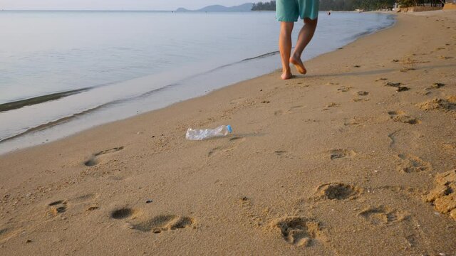 Man throw out plastic bottle garbage on sand beach. Environmental and water pollution