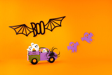Obraz na płótnie Canvas Happy halloween holiday concept. Halloween handmade paper decorations, spiders, ghosts in car, bats, boo text on orange background. Halloween festival party, greeting card mockup with copy space.