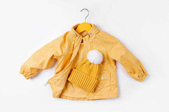 Yellow Jacket Hanging Hanger With Hat On White Background. Cute Autumn Kids Outfit.