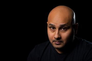 Obraz premium Portrait of a bald man looking at camera against dark black background.