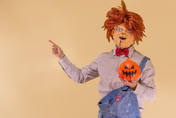 Muñeco diabólico con calabaza de Halloween, señalando al fondo marrón, con espacio para texto.