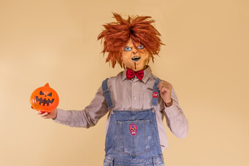 Muñeco diabólico con la calabaza de Halloween, en fondo marrón con espacio para texto.