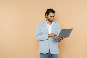 Young white man wearing jacket smiling while posing with laptop