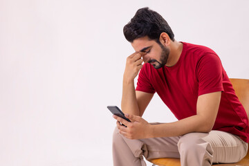 A TENSED MAN SITTING ALONE WHILE HOLDING MOBILE PHONE