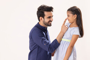 A FATHER LOOKING AT DAUGHTER WHILE CHEERFULLY PLAYING WITH HER