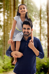 A FATHER CARRYING DAUGHTER WHILE STANDING OUTDOOR