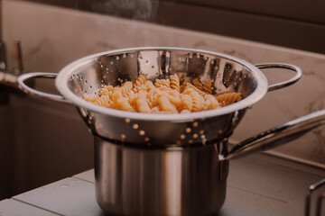 Hot freshly cooked pasta. Boiled makaroni at modern high-tech kitchen with gray kitchen sink