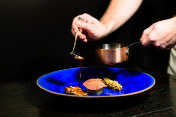Quail, onion, apple, celery root plated in a restaurant on a blue dish, neatly distributed