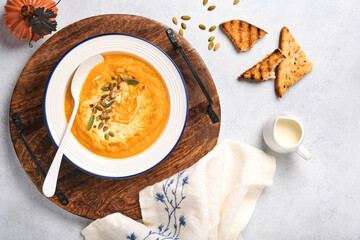 Pumpkin traditional soup with creamy silky texture with sage leaves and red pepper in white plate or bowl. Light grey background. Copy space. Mock up. Top view, flat lay.