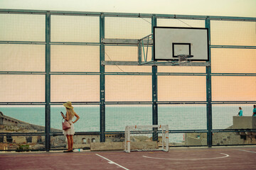 Young traveler girl play basketball inside the fortress with sea on the background. Popular tourist destination, tourists take pictures of medieval fortification. Gorgeous stone building in Dubrovnik