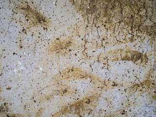 textured old gray concrete background stained with beige stucco with scratches and holes.
