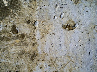 textured old gray concrete background stained with beige stucco with scratches and holes.