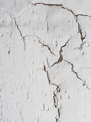 many cracks on the light wall. Textured background. Vertical