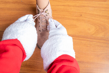 Santa Claus is helping a little girl tie her pink shoelaces