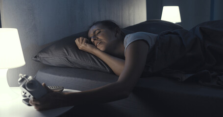 Woman suffering from insomnia and checking the time