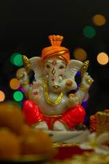 Murti or Moorti Of Ganpati Bappa Morya Hindu God Lord Ganesha In Orange Pagdi For Worship On Diwali Puja New Year Deepawali Ganesh Chaturthi Or Shubh Deepavali Pooja. Black Background