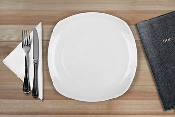 Fasting and prayer. Christian biblical concept, empty plate with Holy Bible.