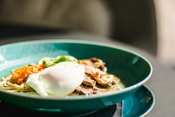 Beef ramen soup with poached egg and vegetables at a restaurant
