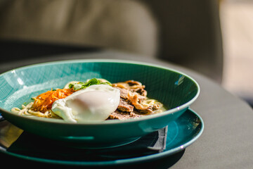 Beef ramen soup with poached egg and vegetables at a restaurant