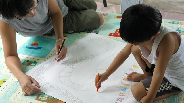 Authentic asian cute child boy and father writing, painting together Kid doing number game paper. Concept of children education, family activity, relationship, fatherhood, learning, togetherness.