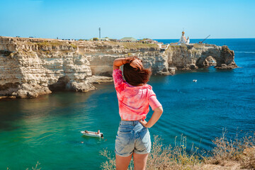 A beautiful young woman enjoys a picturesque seascape with azure water on the west coast of Crimea