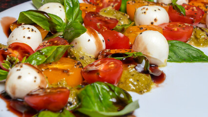 Defocused background of caprese salad. Healthy meal with cherry tomatoes, mozzarella balls, spices and basil.
