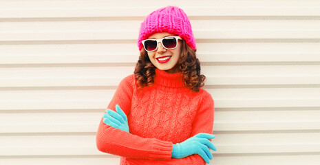 Winter portrait of happy smiling young woman wearing a knitted sweater, pink hat having fun on white background