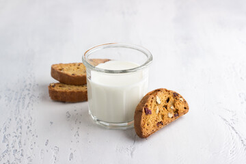 Glass of fresh milk and homemade pumpkin biscotti with cranberries and nuts on light gray background