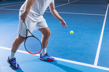 Cropped image of tennis player in uniform with racket ready to hit ball isolated over gym background