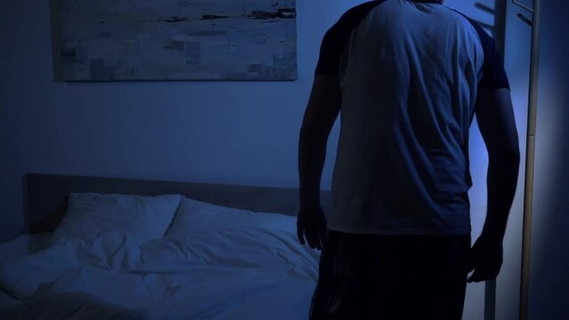 slow motion of sleepy man in pajamas going to bed at night