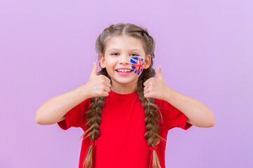 A student with a British flag painted on her cheek gives a thumbs up.