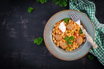 Italian traditional ditalini pasta with meatballs in tomato sauce and vegetables in bowl.  Ditalini pasta and beef balls  with marinara tomato sauce. Top view. Flat lay.